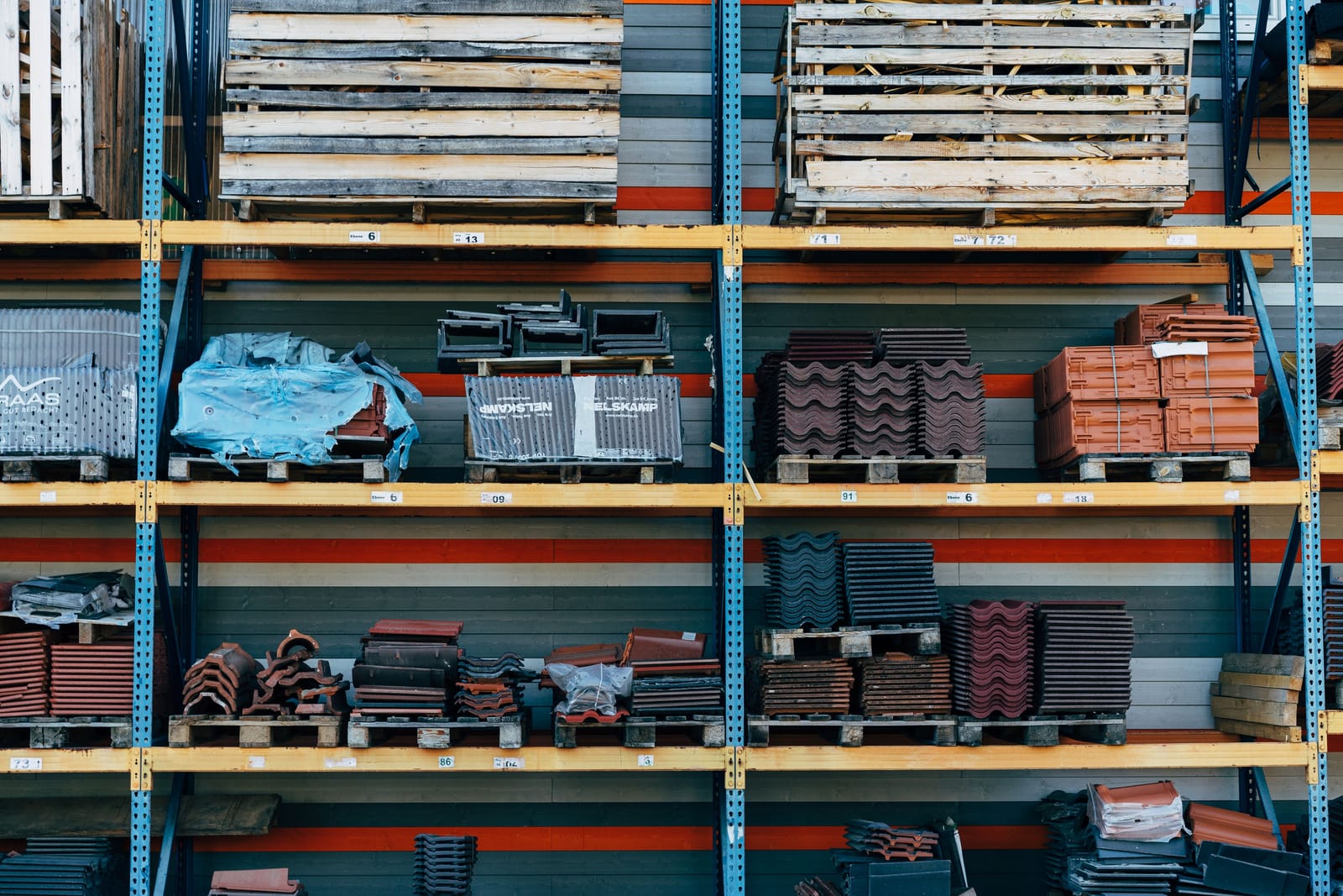 Pallets of parts and tiles on the yellow beams of a warehouse rack