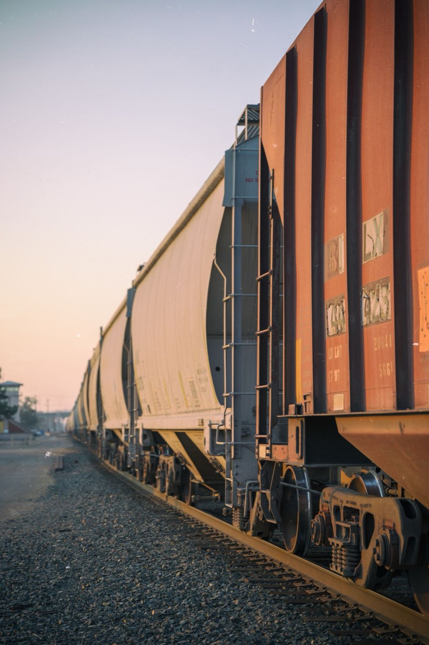 A string of covered hopper cars standing on a siding at dusk